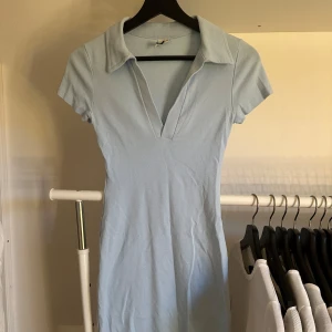 Ljusblå klänning - Ljusblå kort klänning med v-urringning samt krage. Använd ett fåtal gånger men den har inga defekter.