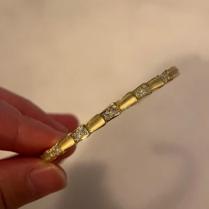 Guldarmband med glittriga detaljer - Elegant guldarmband med fyrkantiga länkar och glittriga detaljer. Perfekt för att ge en lyxig touch till din stil. Armbandet har en stilren design som passar till många tillfällen.