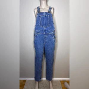 Blå denim byxdress från ASOS - Blå denim byxdress från ASOS med justerbara axelband och en klassisk fickdesign fram och bak. Perfekt för en avslappnad stil med en t-shirt under.