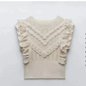 Beige spetsdetaljerad topp - Säljer en elegant beige topp med vackra spetsdetaljer och volanger. Toppen har en unik stickad design och passar perfekt att både klä upp och ner
