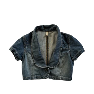 Vintage-inspirerad kort jeansjacka - Superfin kort jeansjacka/bolero med vintage vibes! Perfekt att styla över en klänning eller med en topp och jeans för en cool 2000-talslook. Har en knapp framtill och en snygg, unik krage. Endast använd vid ett fåtal tillfällen och är i bra skick!