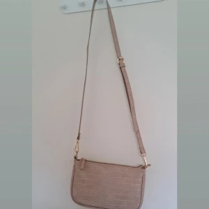Beige axelväska med krokodilmönster - Snygg beige axelväska med krokodilmönster och justerbar axelrem. Väskan har en dragkedja! Använt några gånger 💫