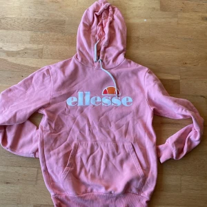 Rosa hoodie från Ellesse - Säljer en snygg rosa hoodie från Ellesse med deras ikoniska logga tryckt på framsidan. Perfekt för en avslappnad stil.