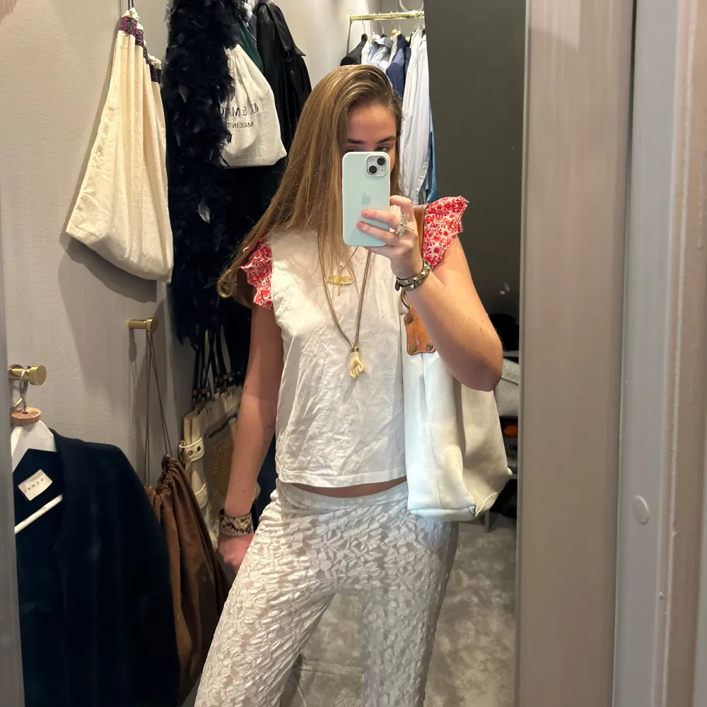 Säljer en söt zara vit topp med röda spetsdetaljer på ärmarna. Toppen är ärmlös och har en avslappnad passform. Perfekt för varma dagar och kan enkelt matchas med olika outfits.. Yläosat.