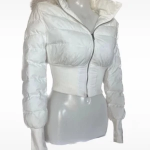 Vit croppad dunjacka med huva - Snygg vit croppad dunjacka med dragkedja och fluffig huva. Jackan har långa ärmar och en tight passform ☺️