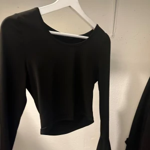 Svart långärmad croppad topp - Snygg svart långärmad croppad topp i ett mjukt och stretchigt material. Perfekt för en stilren look. Passar bra till både jeans och kjol.