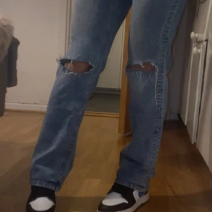 Low straight jeans -  Passar Xs/S Säljer ett par blå jeans med slitningar på knäna. De har en straight passform och är perfekta för en avslappnad stil. Jeansen är i en klassisk blå färg och har en bekväm midwaist.
