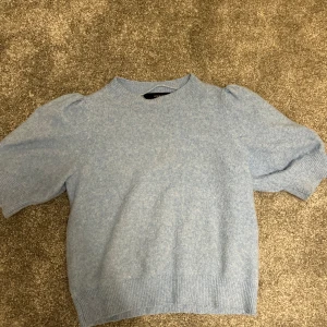 Ljusblå stickad tröja - Säljer en söt ljusblå stickad tröja med puffiga ärmar. Tröjan har en rund halsringning och är perfekt för kyligare dagar. Den är både stilren och bekväm, vilket gör den till ett mångsidigt tillskott i garderoben. Passar bra till jeans eller kjol för en avslappnad look.