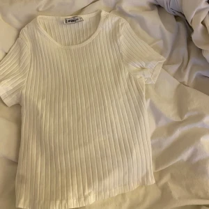 Vit ribbad topp med knyte  - Säljer en vit ribbad topp från NEW YORKER. Toppen är kortärmad med en snygg knytning i ryggen. Perfekt för en stilren och trendig look. Det är storlek S i toppen men passar xs också.💗💗