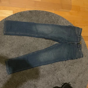 Jack & Jones jeans - Snygga blå jeans från Jack & Jones med klassisk femficksdesign och knappgylf. Perfekta för en avslappnad stil. Märkeslapp baktill och kontrastsömmar ger en cool touch. Strl är 164cm/14y och det är slim fit