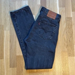 Levis 501 Jeans Svarta/Mörkgrå - Jeans i modellen 501 i färgen Svarta/Mörkgrå från Levis. Storlek: 30 W 34 L, Midja: 38.5cm, Ytterben: 109cm, Benöppning: 18.5cm. Material: 100% Cotton.