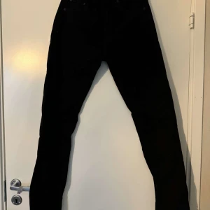 Svarta jeans från Levi's - Snygga svarta jeans från Levi's med klassisk design. De har en rak passform och är perfekta för en stilren look. Levi's-loggan syns tydligt på baksidan.