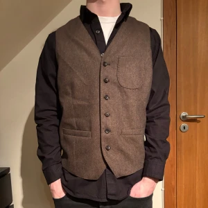 Brun väst från The Tailoring Club - Säljer en stilren brun väst från The Tailoring Club. Modellen är 183cm och bär storleken 52 (L). Hör av dig vid fråga. 
