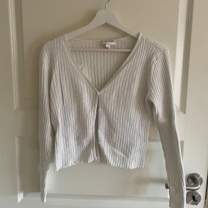 Vit ribbad kofta från Monki - Säljer en stilren vit ribbad kofta från Monki. I storlek L men sitter som S