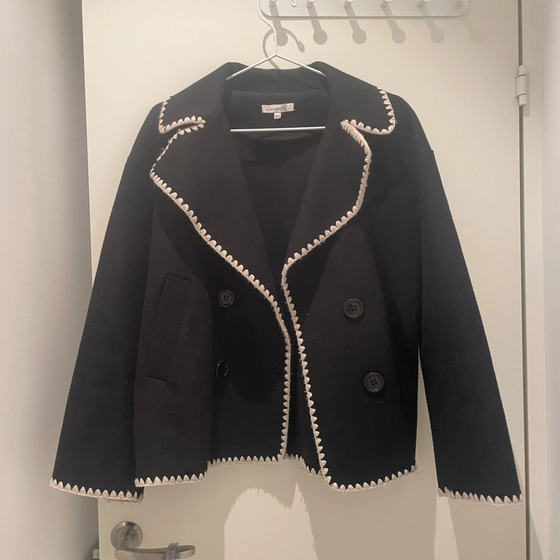 Svart kappa med vita detaljer