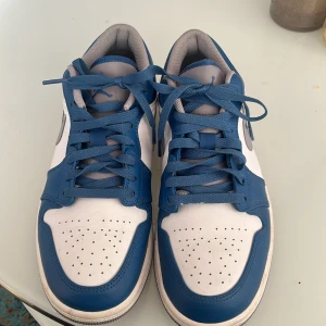 Nike sneakers i blått och vitt. Jordan 1 low true blue - Snygga Nike sneakers i blått och vitt med klassisk design. Skorna har snörning och en stilren Nike-logga på sidan. Skorna är använt max 5 gånger, nästan ingen crease. Säljer pågrund av att de är för små och använder aldrig. Ny pris 2500