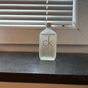 CK One parfym från Calvin Klein - Säljer en klassisk CK One parfym från Calvin Klein. Flaskan är frostad och har en minimalistisk design med en enkel skruvkork. Perfekt för den som gillar en fräsch och unisex doft.
