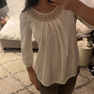 Vit blus med spetsdetaljer - Säljer en elegant vit blus med spetsdetaljer runt halsringningen. Blusen har trekvartsärmar och ett löst fall som ger en bekväm passform.❤️