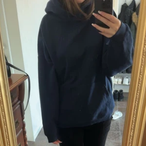 Mörkblå hoodie - Säljer en stilren mörkblå hoodie med en bekväm passform. Den har en klassisk känguruficka framtill och en rymlig huva. Perfekt för en avslappnad look.
