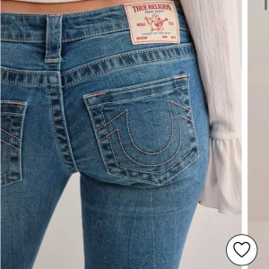 Blå jeans från True Religion - Snygga blå jeans från True Religion med ikonisk broderad detalj på bakfickorna sömmarna är rosa . De har en låg midja och en bootcut-stil, lite slitna vid änden då de är för långa för mig. Kostar 1400kr original