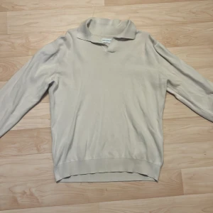 Beige pikétröja från These Glory Days - Säljer en stilren beige pikétröja från These Glory Days. Tröjan har långa ärmar och en klassisk krage. Perfekt för en avslappnad men ändå snygg look. Passar bra till både jeans och chinos.