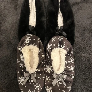 Mysiga tofflor - Säljer två par mysiga tofflor. De har en mjuk insida i fuskpäls och en söt rosett på ovansidan. Perfekta för kalla dagar inomhus. 1 par för 15kr eller båda par för 20kr