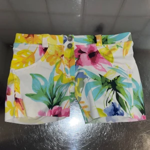 Blommiga shorts från Freddy - Snygga blommiga shorts från Freddy i en färgglad mix av rosa, gul, grön och blå. De har en högmidjad passform med två knappar framtill och praktiska fickor både fram och bak. Perfekta för en somrig look! Kan användas till träning eller en vanlig vardag 🌸köptes för 600kr
