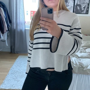 Randig vit och svart tröja - Säljer en snygg randig tröja i beige och svart. Tröjan har långa ärmar och en avslappnad passform med en croppad design. Perfekt för en stilren look.
