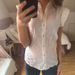 Vit linne blus - Vit blus med volang detalj, bra sommar topp. Från HM i storlek xs men passar s. Kommit till användning en gång. Ny skick i linne tyg.