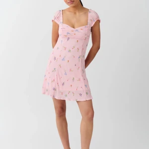 Rosa blommig klänning - Säljer slutsåld Gina tricot  klänning med blommigt mönster och korta ärmar. Den har en smickrande passform med rynkade detaljer vid bysten och en lätt utsvängd kjol. Perfekt för somriga dagar! Kontakta gärna om ni har några funderingar!❤️ 
