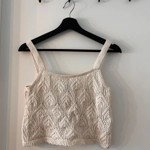 Beige stickad linnetopp från Lindex - Säljer en superfin beige stickad linnetopp från Lindex. Den har ett snyggt mönster och breda axelband. Perfekt för sommardagar när du vill ha något både stilrent och bekvämt. Passar bra till både jeans och kjol!