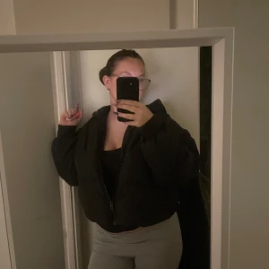 Svart pufferjacka - Säljer en svart pufferjacka storlek XS i nyskick. Den är croppad och har en dragkedja framtill. Perfekt för höst och vinter. Jackan är stilren och praktisk för kyligare dagar. 💕