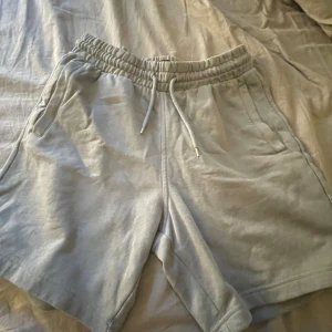 Grå shorts från H&M - Säljer ett par grå shorts från H&M i regular fit. De har en elastisk midja med snöre och praktiska fickor både fram och bak. Perfekta för en avslappnad stil under varma dagar!