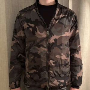 Valentino Garavani Windbreaker  - Valentino Garavani Windbreaker som är varsamt använd, mycket bra skick. Cond: 10/10.  Två olika färger, mörkblå- och grön kamouflage. Vändbar. 100% polyester.  Jag på bilden är 184kg och 78kg. Passar en storlek M men även en ”liten large”.  