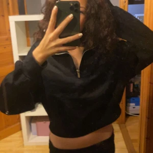 Svart croppad tröja med dragkedja - Säljer en svart croppad tröja med dragkedja framtill. Perfekt för en avslappnad stil och passar bra till både jeans och kjol. Tröjan har långa ärmar och en bekväm passform. Perfekt för höst och vår!