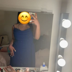 Blå långklänning med slits - Elegant blå långklänning med smala axelband och en stilren slits framtill. Perfekt för festliga tillfällen.