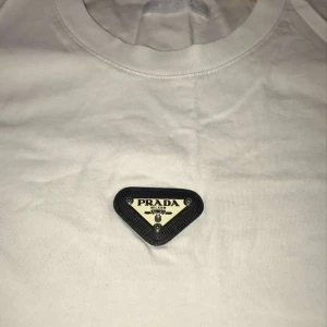 Prada T-shirt  - Äkta prada t-shirt. Storlek S. Den är i helt nytt skick endast Använd ett fåtal gånger. Nytt pris 9300. Säljer den för 1500. Kan sänka pris vid snabb affär 