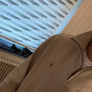 Beige tröja från Polo Ralph Lauren - Säljer en stilren beige tröja från Polo Ralph Lauren med dragkedja och broderad logotyp på bröstet. Perfekt för en avslappnad och elegant look. Säljs då den blivit för liten, storlek S. Billigare vid snabb affär