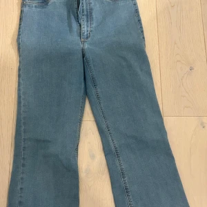 Blå jeans från Jane Boot - Snygga blå jeans från Cubus med hög midja och bootcut-stil. Perfekta för en avslappnad look med en klassisk touch. De har en enkel design med dragkedja och knapp framtill.