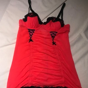 Rosa korsett med spetsdetaljer - Fint hot pink korsett med svarta spetsdetaljer. Den har justerbara axelband och en åtsittande passform som gör att figuren står ut mer. Perfekt för en kul kväll med tex vänner, fester, osv!! 