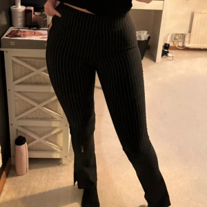 Svarta randiga byxor från NA-KD - Snygga svarta byxor från NA-KD med vita ränder. De har en tight passform och är högmidjade, vilket ger en smickrande siluett. Perfekta för en stilren look.