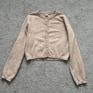 Beige kofta från Lindex - Säljer en stilren beige kofta från Lindex i storlek 158-164 men passar även för 146-152. Koftan har långa ärmar och knappar framtill. Köptes för 299. Använd 1-2 gånger.