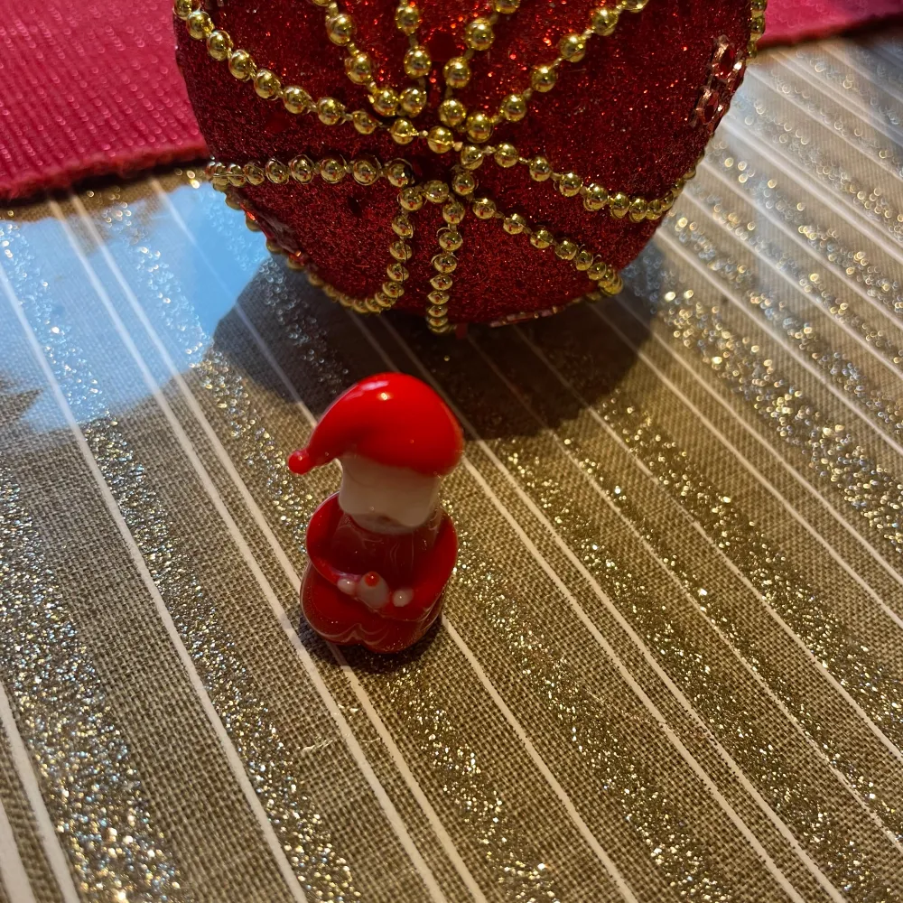 Charmig liten tomtefigur i glas . Perfekt som dekoration till jul. Figuren har en klassisk tomteluva och håller händerna framför sig.. Asusteet.