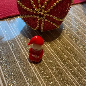 Liten tomtefigur i glas - Charmig liten tomtefigur i glas . Perfekt som dekoration till jul. Figuren har en klassisk tomteluva och håller händerna framför sig.