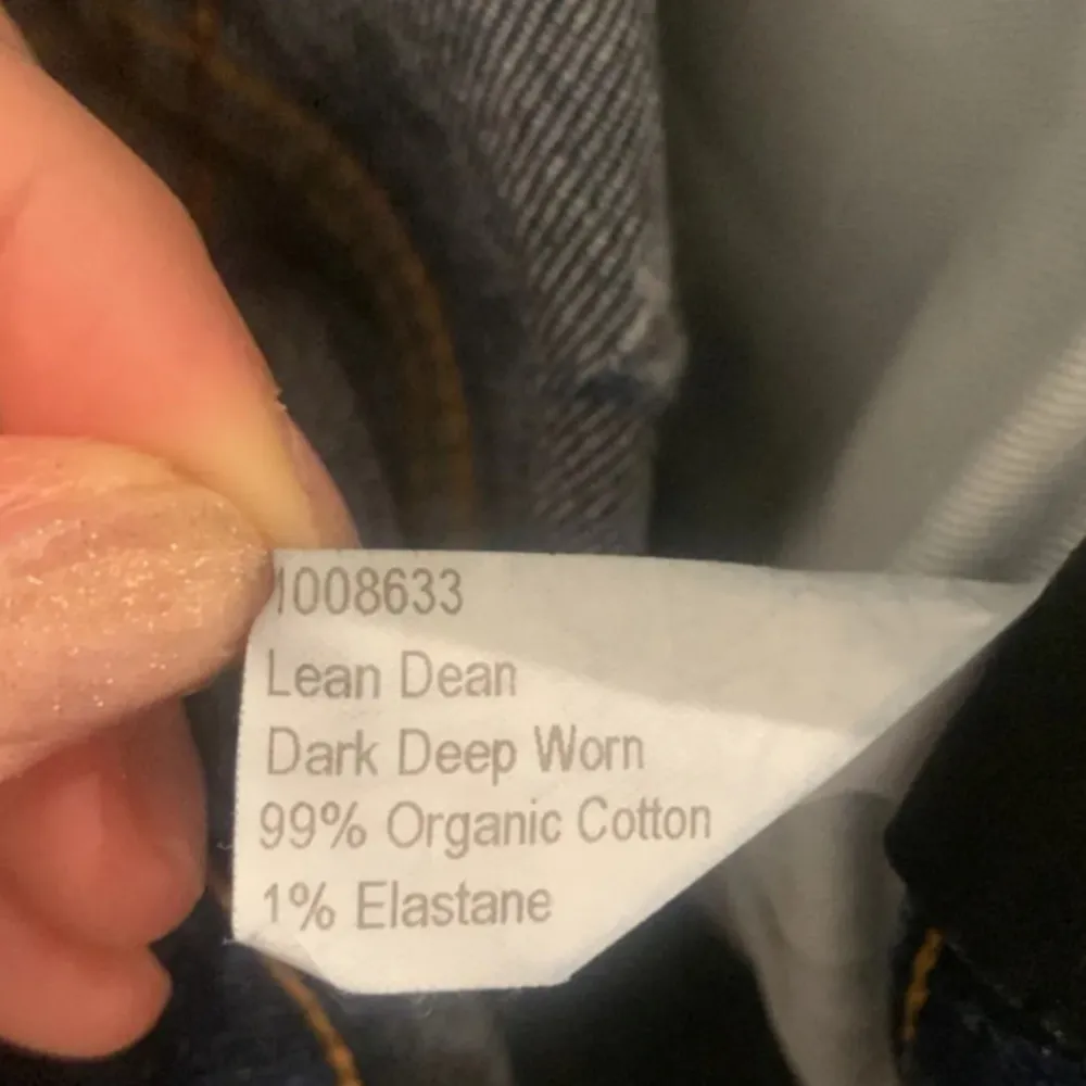 Säljer ett par mörkblå jeans från Nudie Jeans med klassisk femficksdesign och orange sömmar. Jeansen har en slim passform och är tillverkade i denim. Perfekta för en stilren look!. Farkut & Housut.