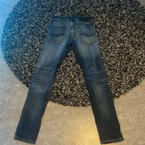 Blå jeans från Jack & Jones - Snygga blå jeans från Jack & Jones i modellen Slim/Glenn. De har en klassisk femficksdesign och en bekväm passform. Perfekta för en stilren look. 27/30