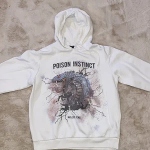 Vit hoodie med tryck - Säljer en vit hoodie med tryck av en orm och texten 'Poison Instinct'. Hoodien har en stor ficka framtill och en bekväm huva. Perfekt för en avslappnad stil.