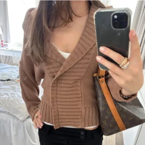 Brun ribbad kofta - Säljer en snygg brun ribbad kofta med omlott-design. Koftan har långa ärmar och en djup v-ringning, perfekt för lager-på-lager-stil. Den är både stilren och bekväm, idealisk för kyligare dagar. Storlek S men skulle säga att den är mer XS💞