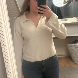 Vit stickad tröja med krage - Säljer en stilren vit stickad tröja med krage och långa ärmar. Perfekt för en avslappnad och bekväm look. Tröjan har en ribbad nederkant som ger en snygg passform.