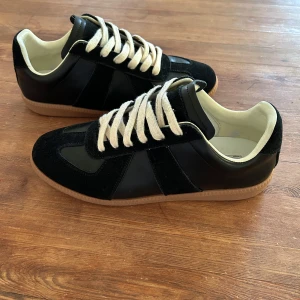 MM GATs SS23 Black Gum ( Maison Margiela ) - Snygga svarta Maison Margiela Sneakers från SS23 Kollektionen i Colorway Black Gum, använd några gånger men håller fortfarande ett mycket fint skick, säljer dessa då de GATs blivit uttjatad och har köpt andra skor.                   Skriv gärna om du har frågor angående skorna eller vill se mer bilder på exempelvis BOX 📦 som medföljer eller KVITTO 🧾 Online, fick nämligen bara visa 5 bilder här… 📲🤝